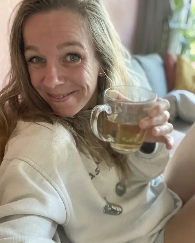 Mirthe van Liere met een kop thee op de bank